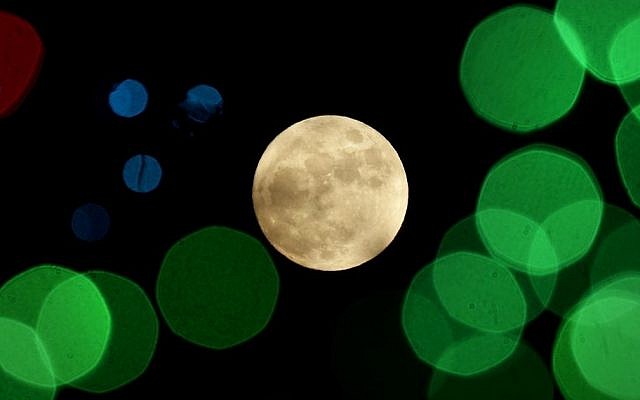 In this Thursday, Dec. 24, 2015, file photo, a nearly-full moon is seen among Christmas lights at a holiday display near Lenexa, Kan. (AP/Charlie Riedel, File)