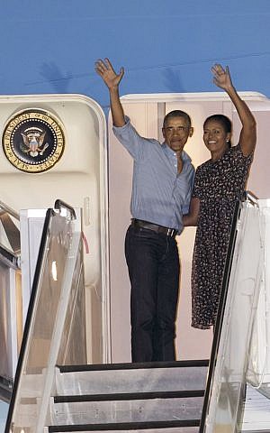 US President Barack Obama and first lady Michelle Obama wave at people from Air Force One as they leave Joint Base Pearl Harbor-Hickam, adjacent to Honolulu, Hawaii, en route to Washington, after their annual family vacation on the island of Oahu, January 1, 2017. (AP/Marco Garcia)