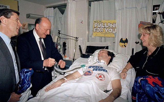 NYPD Officer Steven McDonald, paralyzed after being shot in Central Park earlier in the year, receives a New York Mets baseball jacket from Mets' president Fred Wilpon, left, in McDonald's room in New York's Bellevue Hospital, October 30, 1986. (AP/Mario Suriani) 