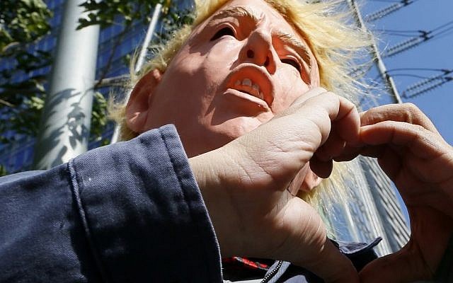 A protester wearing a Donald Trump mask and another protester form a heart as he talks to the media following a brief protest at the Trump Tower hours after Trump was sworn in as the 45th President of the United States, Saturday, Jan. 21, 2017, in the financial district of Makati city east Manila, Philippines. (AP Photo/Bullit Marquez)
