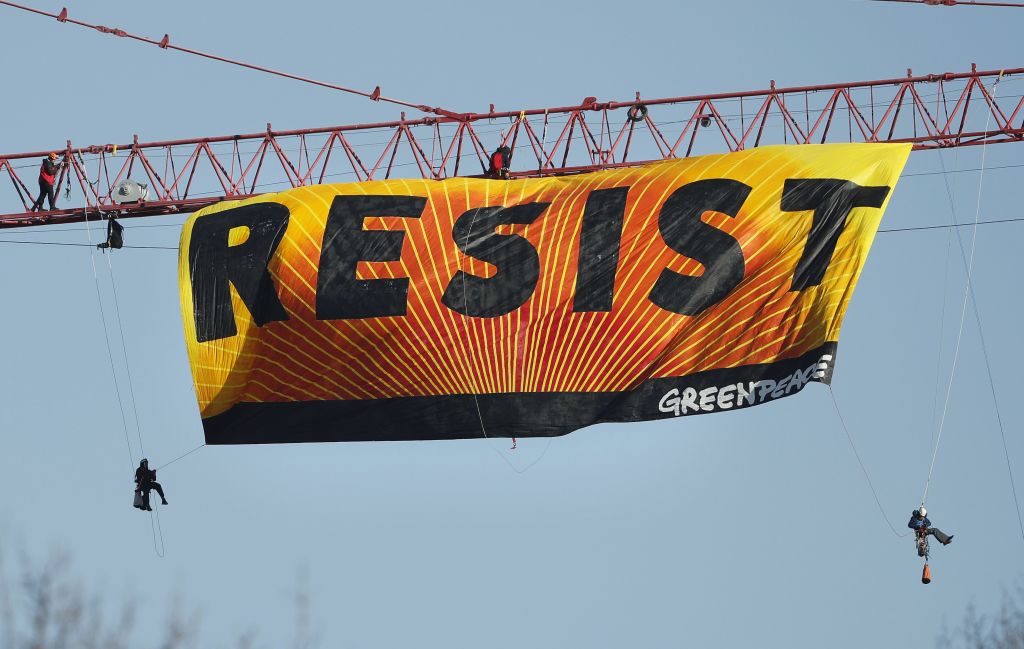 Protest Crane_Horo (1) Protesters unfurl a banner that reads "Resist" at the construction site of the former Washington Post building in Washington, Wednesday, Jan. 25, 2017, after police say protesters climbed a crane at the site refusing to allow workers to work in the area. (AP Photo/Pablo Martinez Monsivais)