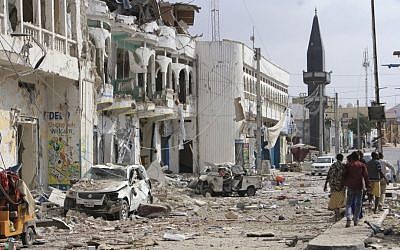 Somalis walk near a hotel and cars destroyed by a car bomb in Mogadishu, Somalia, on Wednesday, January 25, 2017. (AP Photo/Farah Abdi Warsameh)