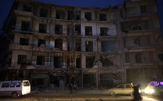 People walk next to a destroyed building in the once rebel-held Shaar neighborhood in the eastern Aleppo, Syria, January 17, 2017. (AP Photo/Hassan Ammar)