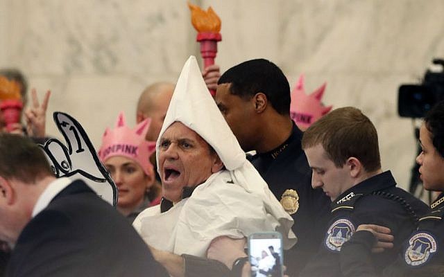 A protester is escorted away by Capitol Hill Police officers, Tuesday, Jan. 10, 2017, in Washington, during the Senate Judiciary Committee's confirmation hearing for Attorney General-designate Sen. Jeff Sessions, R-Alabama. (AP Photo/Alex Brandon)