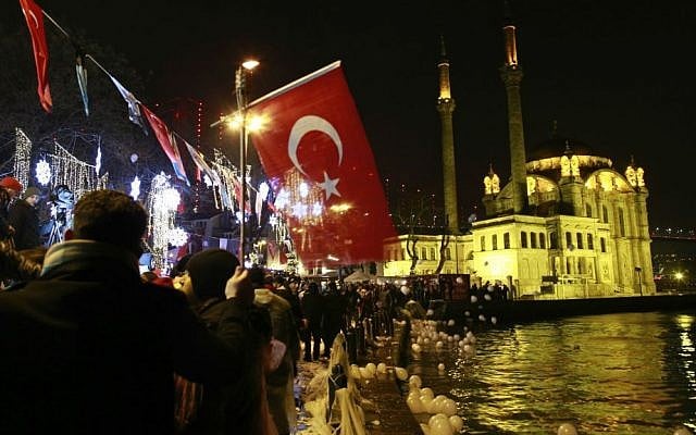 People, some holding Turkish flags, let balloons and lanterns loose into the air in Istanbul's Ortakoy district by the Bosphorus during New Year's celebrations early Sunday, Jan. 1, 2017. (AP Photo/Emrah Gurel)