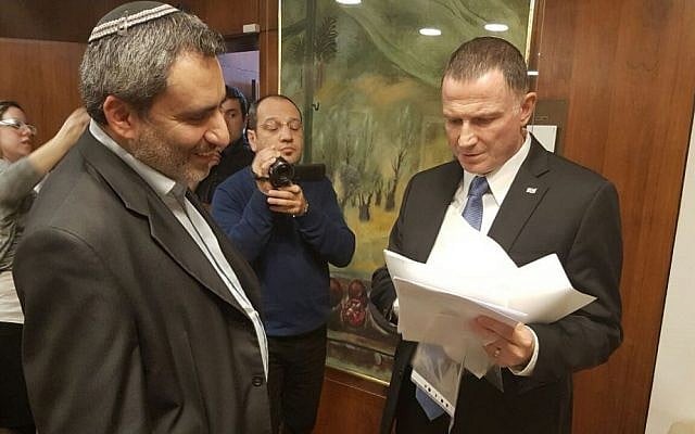 Yuli Edelstein, right, reviewing signatures of 72 MKs supporting a vote on the impeachment of Basel Ghattas, as Zeev Elkin, left, looks on, in the Knesset on January 16, 2017. (Knesset Spokesman's Department)