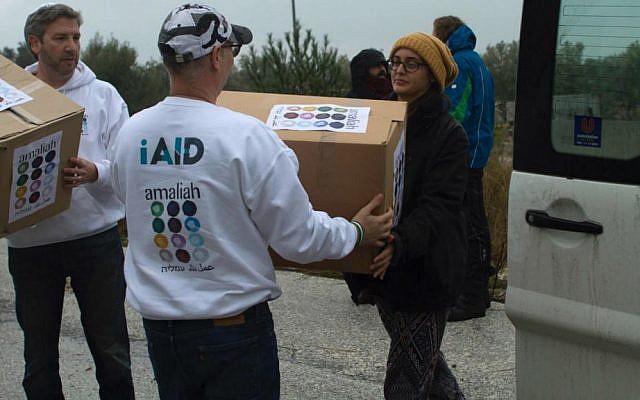 Rabbi Shu Eliovson (left) and Moti Kahana (center) unload relief supplies collected in Israel for refugees with Molly Nixon of Lifting Hands International in Lesbos, Greece. January 19, 2017. (Nave Antopolsky/iAID)