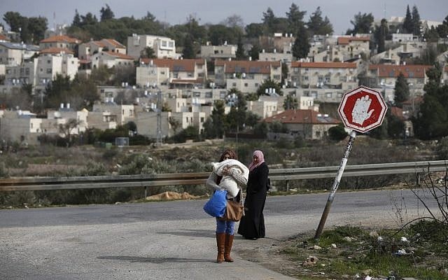 Palestinian women from the Jalazoun refugee camp stand at a crossroad in the West Bank city of Ramallah with the Israeli settlement of Beit El seen behind them, on January 25, 2017. (AFP/Abbas Momani) Palestinian women from the Jalazoun refugee camp stand at a crossroad in the West Bank city of Ramallah with the Israeli settlement of Beit El seen behind them, on January 25, 2017. (AFP/Abbas Momani)