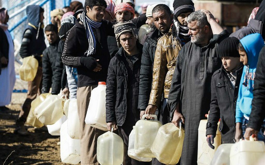 Refugees who fled the Iraqi city of Mosul due to the fighting between government forces and Islamic State (IS) group jihadists, queue for heating fuel at the UN-run al-Hol refugee camp in Syria's Hasakeh province, on January 29, 2017. (Delil Souleiman/AFP)