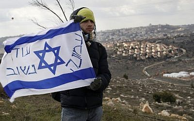 An Israeli settler holds a flag with with "Amona, we will return" written on it at the Amona outpost, northeast of Ramallah, on February 1, 2017, ahead of its evacuation. (AFP Photo/Jack Guez) An Israeli settler holds a flag with with "Amona, we will return" written on it at the Amona outpost, northeast of Ramallah, on February 1, 2017, ahead of its evacuation. (AFP Photo/Jack Guez)