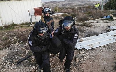 Israeli security forces carry a settler away as they evict residents from the illegal Amona outpost, northeast of Ramallah, on February 1, 2017. (AFP PHOTO/Thomas COEX)