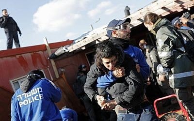 An Israeli policeman carries a young Israeli settler on the second day of an operation to evict the illegal Amona outpost on February 2, 2017. (AFP Photo/Thomas Coex)