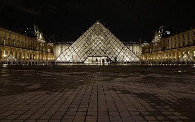 People stand outside the Louvre Pyramid of the Louvre museum at night on February 3, 2017, in Paris, after a French soldier patrolling at the Louvre shot and seriously injured a machete-wielding attacker earlier. (AFP PHOTO / GEOFFROY VAN DER HASSELT)