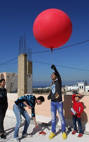 Palestinian refugees fix an inexpensive camera on a red balloon before flying it over different parts of the Burj al-Shamali refugee camp, near the Mediterranean coastal city of Tyre in southern Lebanon, on February 5, 2017. (AFP Photo/Mahmoud Zayyat)