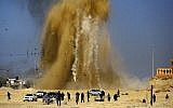 Illustrative: Palestinians run for cover as sand and smoke rise following an Israeli airstrike on a Hamas post in the northern Gaza Strip on February 6, 2017. (Mohammed Abed/AFP)