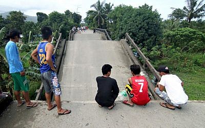 Residents stand on one end of a bridge, linking the city of Surigao to nearby towns, which was damaged after a 6.5-magnitude earthquake struck overnight, in Surigao City in southern island of Mindanao in the Philippines on February 11, 2017. (AFP/Erwin Mascarinas)