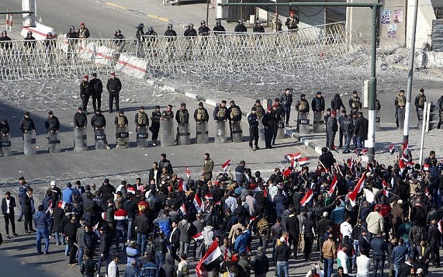 Iraqi security forces stand guard as supporters of the Sadrist movement gather during a demonstration in Baghdad's Tahrir Square on February 11, 2017, to demand the formation of an independent electoral commission. (AFP PHOTO/SABAH ARAR)