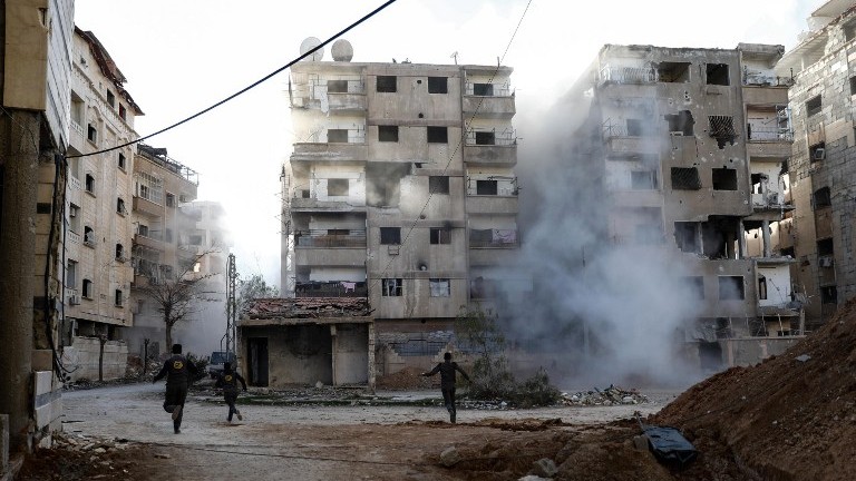 Syrian civil defense volunteers run amid the smoke as they search for survivors following a reported government airstrike on the rebel-held town of Douma, outside Damascus, on February 19, 2017. (AFP Photo/Sameer Al-Doumy) Syrian civil defense volunteers run amid the smoke as they search for survivors following a reported government airstrike on the rebel-held town of Douma, outside Damascus, on February 19, 2017. (AFP Photo/Sameer Al-Doumy)