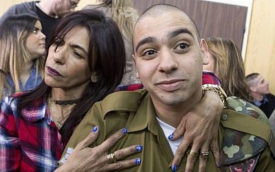 IDF soldier Elor Azaria, right, convicted on the manslaughter of a wounded Palestinian, is embraced by his mother Oshra at the start of his sentencing hearing in a military court in Tel Aviv, February 21, 2017. (AFP/POOL/ JIM HOLLANDER)