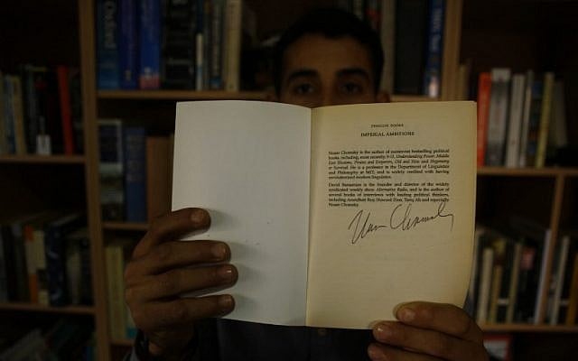 Mossab Abo Toha shows the signature of American philosopher Noam Chomsky, who personally dedicated some books to him, in the library at his family home in Beit Lahia in northern Gaza on February 20, 2017. (AFP Photo/Mohammed Abed)