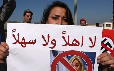 A Lebanese woman holds a placard addressed to France's far-right presidential candidate Marine Le Pen, reading in Arabic "you are not welcome" during a protest in Beirut, on February 21, 2017. (AFP Photo/Patrick Baz)