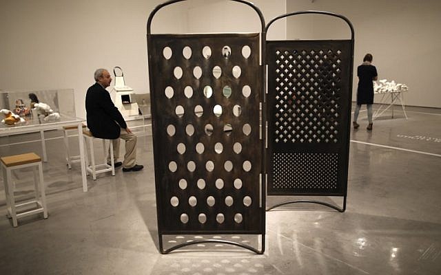 A visitor looks at installations as he sits next next to the "Grater Divide" installation (R) by artist Mona Hatoum, at the No Place Like Home exhibition in the Israel Museum in Jerusalem on February 26, 2017. (AFP PHOTO / MENAHEM KAHANA)