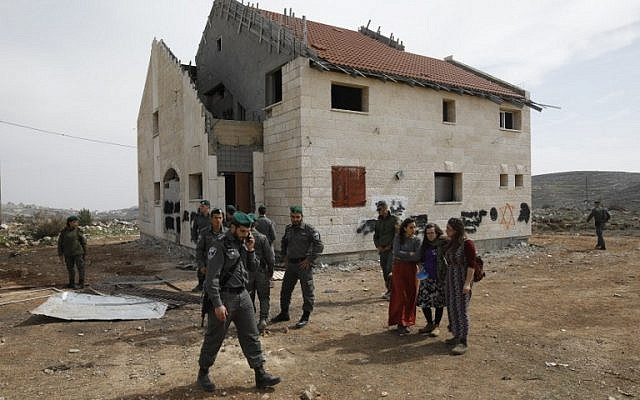 Israeli border guards and youths gather on February 27, 2017 outside a house slated for demolition in the Ofra settlement in the West Bank. (AFP/MENAHEM KAHANA)