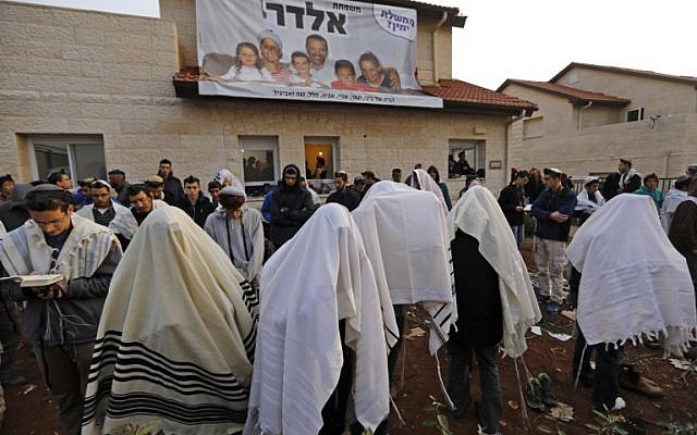 Young right-wing activists pray in front a house which is due to be emptied and demolished in the West Bank settlement of Ofra, on February 28, 2017. (Menahem Kahana/AFP Photo)