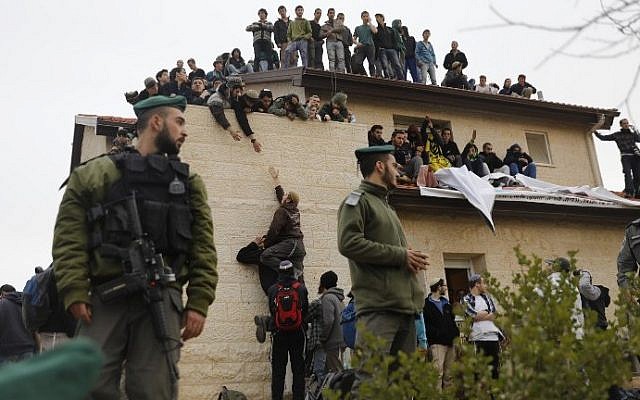 Israeli security forces stand guard as right-wing activists take positions on the rooftop of a home slated for demolition during an operation to clear out nine houses in the Jewish settlement of Ofra, in the West Bank, on February 28, 2017. (Menahem Kahana/AFP Photo)