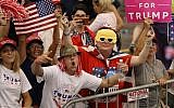A woman shows off her middle fingers as she and others look on at the media during a campaign rally by President Donald Trump at the AeroMod International hangar at Orlando Melbourne International Airport on February 18, 2017 in Melbourne, Florida. (Joe RaedleAFP)