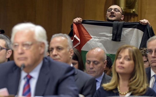 A protestor, holding a Palestinian flag, interrupts David Friedman, nominated to be U.S. Ambassador to Israel, as he testifies on Capitol Hill in Washington, Thursday, Feb. 16, 2017, at his confirmation hearing before the Senate Foreign Relations Committee. (AP Photo/Susan Walsh)