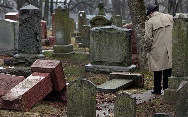 People walk through toppled graves at Chesed Shel Emeth Cemetery in University City, Mo., on Tuesday, Feb. 21, 2017. Authorities in Missouri are investigating after dozens of headstones were tipped over at the Jewish cemetery near St. Louis. (Robert Cohen /St. Louis Post-Dispatch via AP) People walk through toppled graves at Chesed Shel Emeth Cemetery in University City, Mo., on Tuesday, Feb. 21, 2017. Authorities in Missouri are investigating after dozens of headstones were tipped over at the Jewish cemetery near St. Louis. (Robert Cohen /St. Louis Post-Dispatch via AP)
