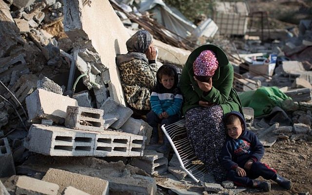 A Bedouin family sits in the ruins of their demolished home in the Bedouin village of Umm al-Hiran, southern Israel, January 18, 2017. (Hadas Parush/Flash90)