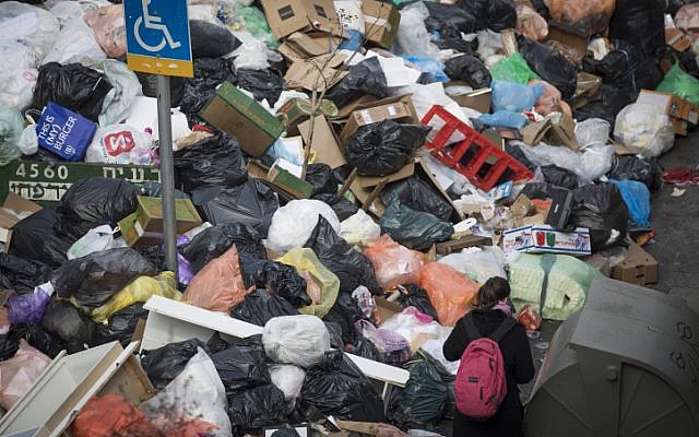 People walk past piles of garbage caused by a strike of the Jerusalem municipality in central Jerusalem, on January 31, 2017. (Yonatan Sindel/Flash90)