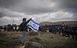 A man holds Israeli flag as Israeli security forces gather ahead of the evacuation of the illegal outpost of Amona, on February 1, 2017. (Miriam Alster/Flash90)