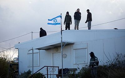 Israeli settlers stand on a rooftop during an evacuation operation at the illegal Israeli outpost of Amona on February 1, 2017. (Miriam Alster/FLASH90) 