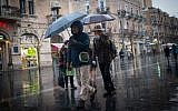 People walk in the rain on Jaffa street in downtown Jerusalem on February 14, 2017, as a rain storm hits the country. (Yonatan Sindel/Flash90)