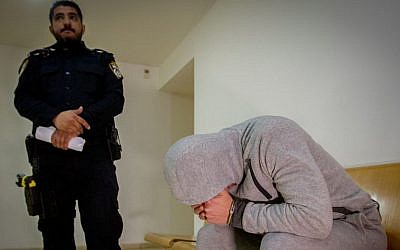 A man suspected of elder abuse sits outside the courtroom as he arrives for a court hearing at the Haifa court on February 19, 2017. Flash90)