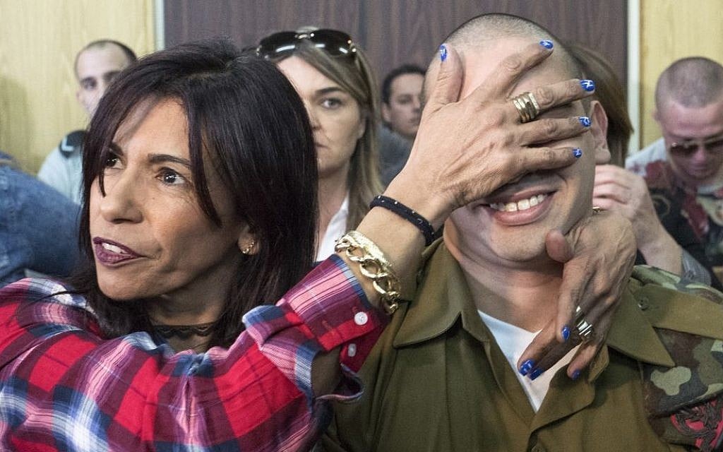 IDF Sgt. Elor Azaria, who shot dead a disarmed and injured Palestinian attacker in the West Bank city of Hebron in March 2016, is surrounded by family and friends as he awaits to hear his sentence in a courtroom at the Kirya military base in Tel Aviv, on February 21, 2017 (Jim Hollander/POOL)