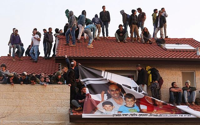 Protesters sit on a rooftop of a home during an operation to evacuate nine homes in the Jewish settlement of Ofra, in the West Bank, February 28, 2017. (Hadas Parush/Flash90) 