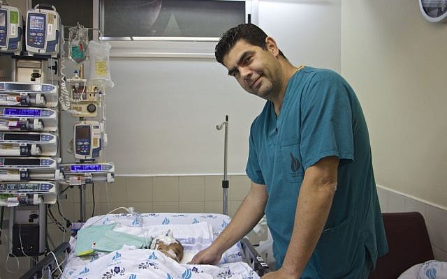 Dr Hagi Dekel, an Israeli cardiac surgeon at the Wolfson Medical Center in Holon, stands next to Yacub, a two-year-old Afghan whose life he saved, on February 23, 2017 (Dov Lieber / Times of Israel)