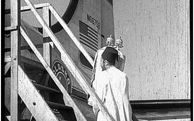 A Yemeni Jew leaving aboard a flight on Operation Magic Carpet, with a Torah in his arms. (Courtesy JDC)