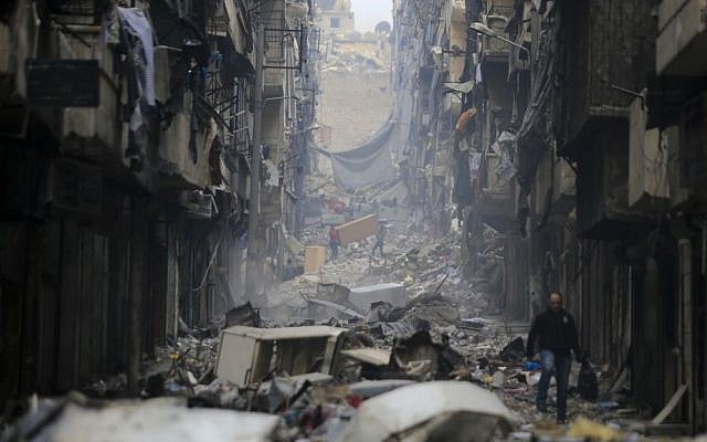 In this January 20, 2017 photo, residents walk amid the rubble of the once rebel-held Salaheddine neighborhood of eastern Aleppo, Syria. (AP Photo/Hassan Ammar)