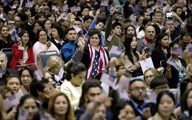 In this Wednesday, Feb. 15, 2017, file photo, people wave US flags during a naturalization ceremony at the Los Angeles Convention Center, in Los Angeles, California. (AP Photo/Jae C. Hong, File)