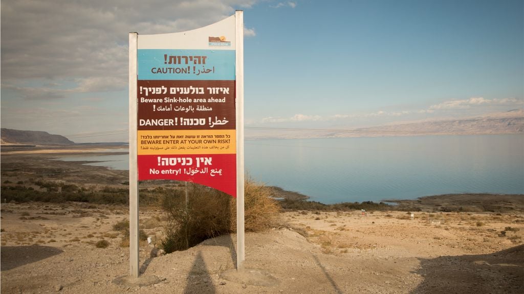A sign warning visitors of the danger of sinkholes around the shores of the Dead Sea on January 3, 2017. (Melanie Lidman/Times of Israel) A sign warning visitors of the danger of sinkholes around the shores of the Dead Sea on January 3, 2017. (Melanie Lidman/Times of Israel)