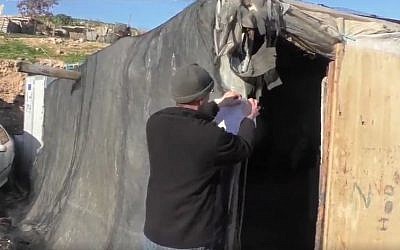 Video still of IDF soldier serving demolition order on illegal structure in Khan al-Ahmar Bedouin camp north east of Jerusalem (Screen capture: Twitter)