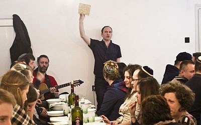 Adam Schonberger, standing, with other participants at the 2016 seder dinner at the Aurora Jewish community center in Budapest, April 22, 2016. (Courtesy of Marom via JTA)