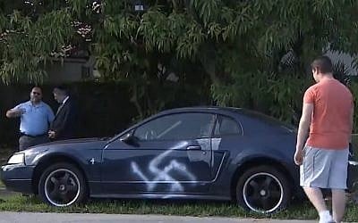 Local residents inspect a swastika spray-painted on the side of a car in a predominantly Jewish neighborhood of Boca Raton, Florida on February 12, 2017. (screen capture: 7News Miami)