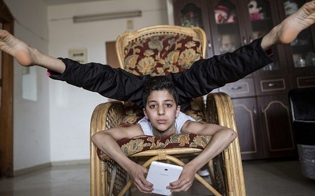 This file photo taken on April 28, 2016 shows then-twelve-year-old Palestinian teenager Mohammed al-Sheikh showing off his contortionist skills at his home in Gaza city. / AFP PHOTO / MAHMUD HAMS This file photo taken on April 28, 2016 shows then-twelve-year-old Palestinian teenager Mohammed al-Sheikh showing off his contortionist skills at his home in Gaza city. / AFP PHOTO / MAHMUD HAMS