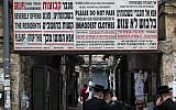 Ultra-Orthodox men stand under a sign stating that the entrance of groups and of people in clothes that are not modest offend the feeling of the citizens in Meah Shearim,  Jerusalem, on March 7, 2013. (Nati Shohat/Flash 90)